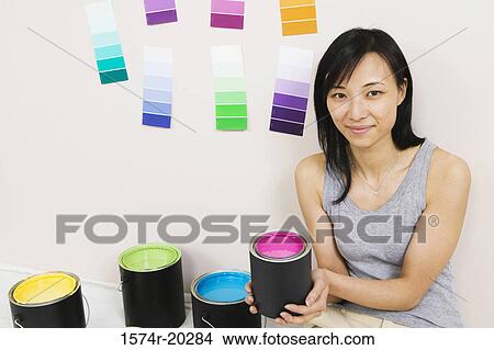 Portrait of a young woman holding a paint can with color swatches on a wall View Large Photo Image Picture - Portrait of a young woman holding a paint can with color swatches on a wall. Fotosearch