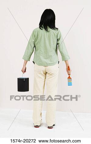 Rear view of a woman holding a paint can and a paintbrush View Large Photo Image Stock Image - Rear view of a woman holding a paint can and a paintbrush. Fotosearch
