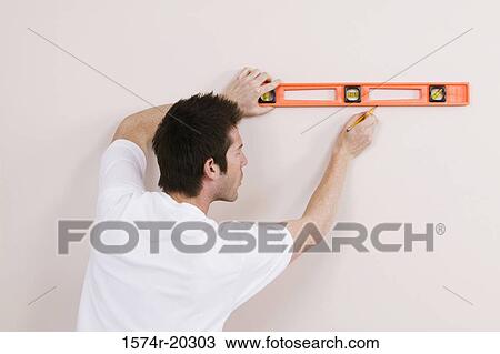 Rear view of a young man using a spirit level to mark on a wall View Large Photo Image Stock Image - Rear view of a young man using a spirit level to mark on a wall. Fotosearch