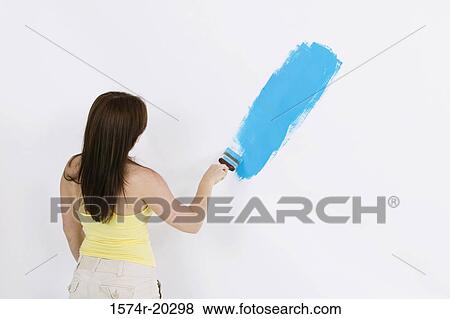 Rear view of a young woman painting a wall View Large Photo Image Stock Photo - Rear view of a young woman painting a wall. Fotosearch
