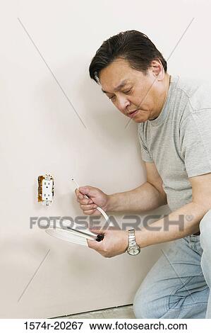 Side profile of a mid adult man holding wire and a screwdriver near a power outlet View Large Photo Image Stock Photo - Side profile of a mid adult man holding wire and a screwdriver near a power outlet. Fotosearch