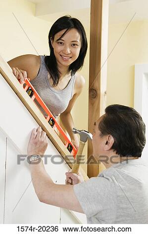 Side profile of a mid adult man using a hammer with a young woman helping him View Large Photo Image Stock Photograph - Side profile of a mid adult man using a hammer with a young woman helping him. Fotosearch