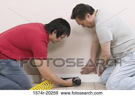 Side profile of a young man and a mid adult man using a drill on a wall View Large Photo Image Stock Photo - Side profile of a young man and a mid adult man using a drill on a wall. Fotosearch