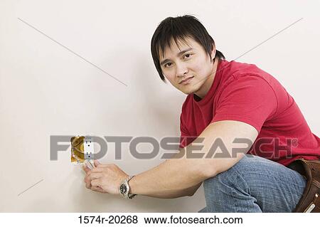 Side profile of a young man holding a screw driver and repairing a power outlet View Large Photo Image Stock Photo - Side profile of a young man holding a screw driver and repairing a power outlet. Fotosearch