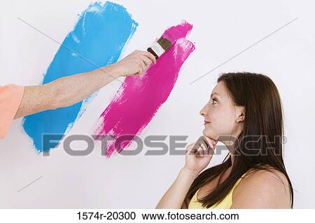 Side profile of a young woman looking at a person's hand painting a wall View Large Photo Image Stock Image - Side profile of a young woman looking at a person's hand painting a wall. Fotosearch