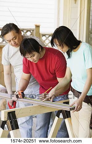 Young man marking on a plank with a young woman and a mid adult man standing beside him View Large Photo Image Stock Image - Young man marking on a plank with a young woman and a mid adult man standing beside him. Fotosearch