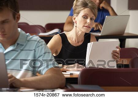 Close-up of a mid adult woman sitting in a lecture hall and peeking at a young man during an exam View Large Photo Image Stock Photo - Close-up of a mid adult woman sitting in a lecture hall and peeking at a young man during an exam. Fotosearch