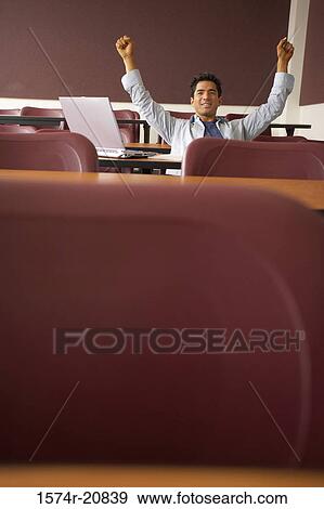 College student sitting in a lecture hall with his arms raised View Large Photo Image Stock Photo - College student sitting in a lecture hall with his arms raised. Fotosearch