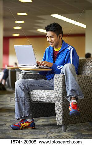Stock Photography - College student sitting in an armchair and using a laptop. Fotosearch