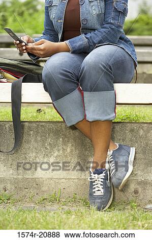 Stock Photo - Low section view of a college student using a mobile phone. Fotosearch