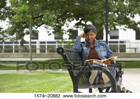 Portrait of a college student sitting on a bench and holding a book View Large Photo Image Stock Image - Portrait of a college student sitting on a bench and holding a book. Fotosearch