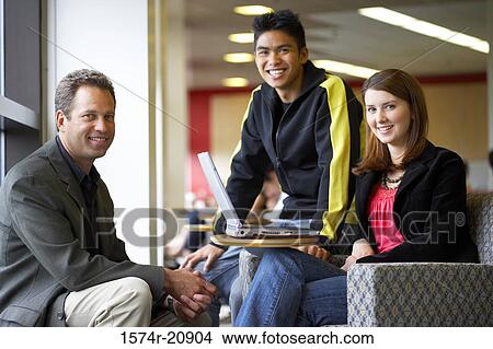 Picture - Portrait of a professor sitting with his students and smiling. Fotosearch