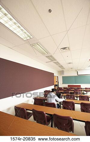 Stock Photography - Rear view of a college student sitting in a lecture hall and using a laptop. Fotosearch