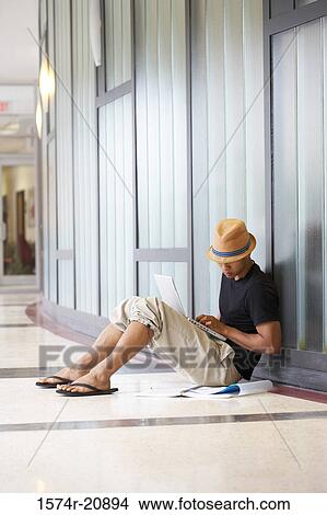 Side profile of a college student sitting in a corridor and using a laptop View Large Photo Image Picture - Side profile of a college student sitting in a corridor and using a laptop. Fotosearch