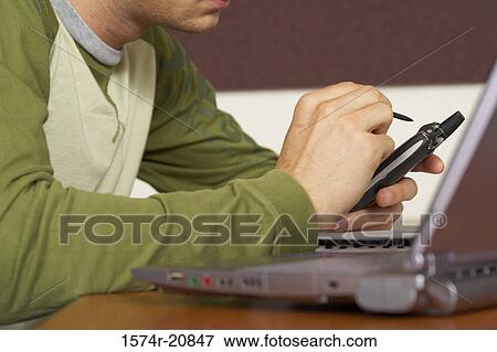 Stock Photo - Side profile of a college student using a mobile phone with a digitized pen. Fotosearch
