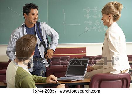 Stock Photo - Side profile of a professor and two college students smiling in a lecture hall. Fotosearch