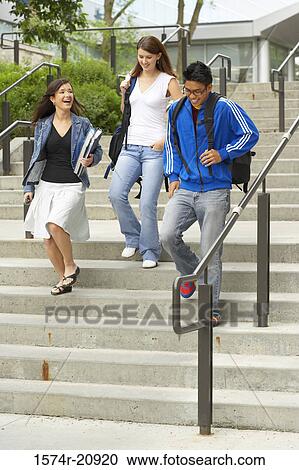 Three college students moving down a staircase View Large Photo Image Stock Image - Three college students moving down a staircase. Fotosearch