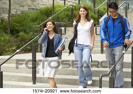 Three college students moving down a staircase View Large Photo Image Stock Image - Three college students moving down a staircase. Fotosearch