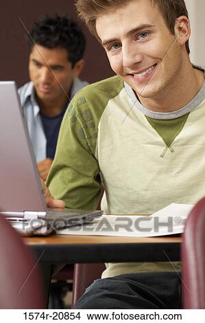 Picture - Two college students sitting in a lecture hall and using laptops. Fotosearch