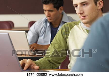Stock Image - Two college students sitting in a lecture hall and using laptops. Fotosearch