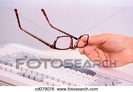 Stock Photograph - Hand holding reading glasses. Fotosearch