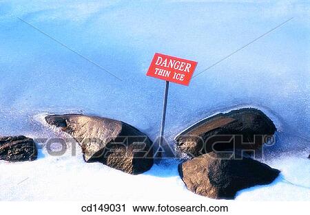 Stock Image - A sign warning of thin ice on a pond in winter.. Fotosearch