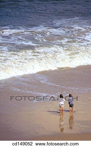 A young boy and a girl, stand on a beach looking out at the waves of the ocean. View Large Photo Image Stock Image - A young boy and a girl, stand on a beach looking out at the waves of the ocean.. Fotosearch