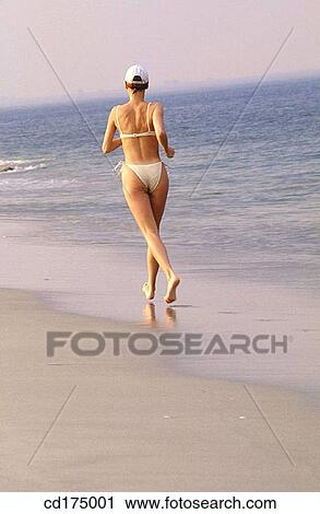 Stock Image - back view, beach, bathing-suit, barefoot, activity. Fotosearch
