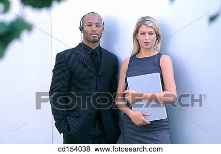 Stock Photo - Black executive with headset and businesswoman looking at camera. Fotosearch