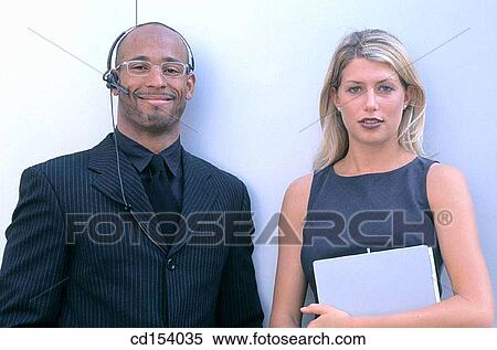 Black executive with headset and businesswoman looking at camera View Large Photo Image Stock Photography - Black executive with headset and businesswoman looking at camera. Fotosearch
