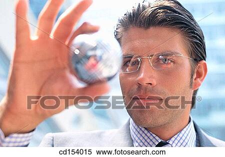 Stock Photography - Businessman looking at silver ball. Fotosearch