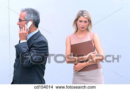 Businessman talking on cell phone, businesswoman looking at camera View Large Photo Image Picture - Businessman talking on cell phone, businesswoman looking at camera. Fotosearch