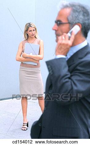 Businessman talking on cell phone, businesswoman in the background View Large Photo Image Stock Image - Businessman talking on cell phone, businesswoman in the background. Fotosearch