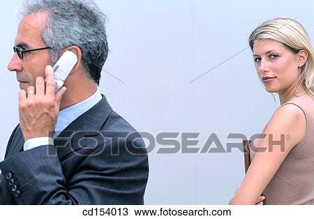 Businessman talking on cell phone, businesswoman in the background looking at camera View Large Photo Image Stock Image - Businessman talking on cell phone, businesswoman in the background looking at camera. Fotosearch