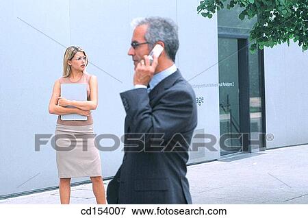 Businessman talking on cell phone, businesswoman in the background View Large Photo Image Stock Photo - Businessman talking on cell phone, businesswoman in the background. Fotosearch