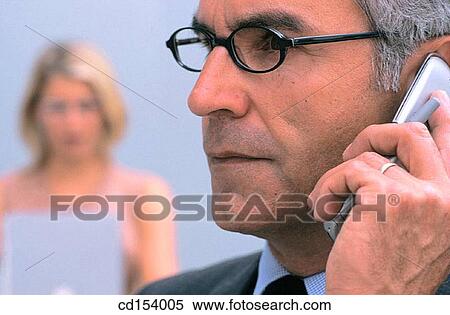 Businessman talking on cell phone, businesswoman in the background, blurred View Large Photo Image Stock Photography - Businessman talking on cell phone, businesswoman in the background, blurred. Fotosearch