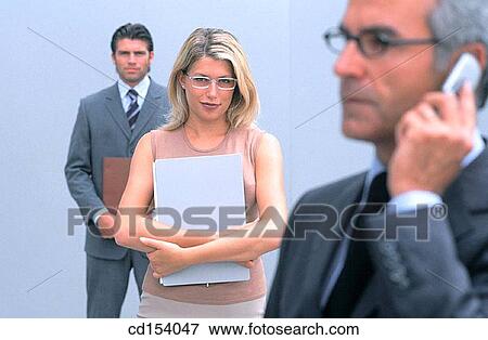 Businessman talking on cell phone, two businesspeople in the background looking at camera View Large Photo Image Stock Photo - Businessman talking on cell phone, two businesspeople in the background looking at camera. Fotosearch