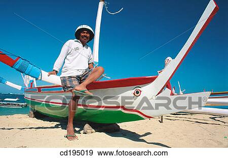 Stock Photo - Outrigger boat helmsman. Sanur Beach. Bali. Indonesia. Fotosearch