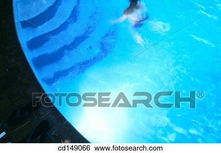 Stock Photograph - Partial view of a swimming pool with a human figure in the water.. Fotosearch