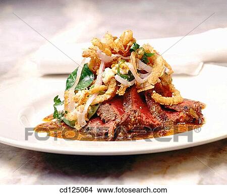 Steak topped with onion rings and salad greens View Large Photo Image Picture - Steak topped with onion rings and salad greens. Fotosearch