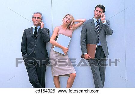 Stock Photography - Two businessmen talking on cell phone, woman bored. Fotosearch
