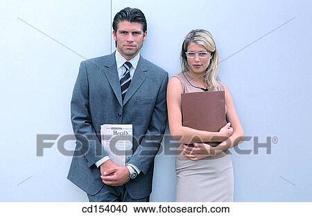 Stock Image - Two businesspersons with files looking at camera. Fotosearch