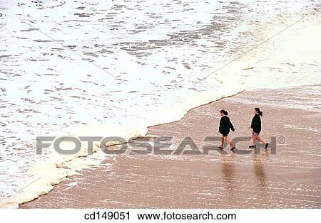 Two young teen age girls walking on the beach toward the waves. View Large Photo Image Stock Image - Two young teen age girls walking on the beach toward the waves.. Fotosearch
