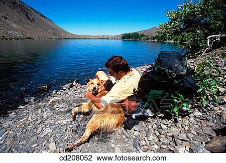 A backpacker rests with his dog at the edge of a mountain lake View Large Photo Image Stock Image - A backpacker rests with his dog at the edge of a mountain lake. Fotosearch