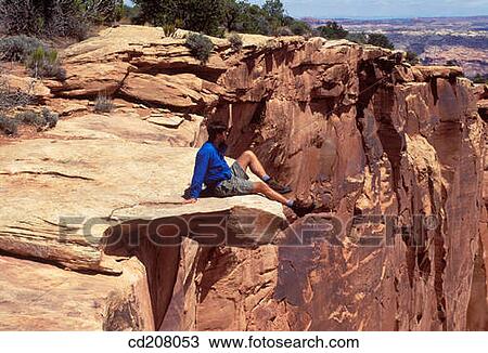 A hiker sitting on the edge of a cliff near Moab, Utah, USA View Large Photo Image Stock Image - A hiker sitting on the edge of a cliff near Moab, Utah, USA. Fotosearch