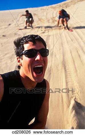 A man yelling while sandboarding with his friends View Large Photo Image Stock Photograph - A man yelling while sandboarding with his friends. Fotosearch