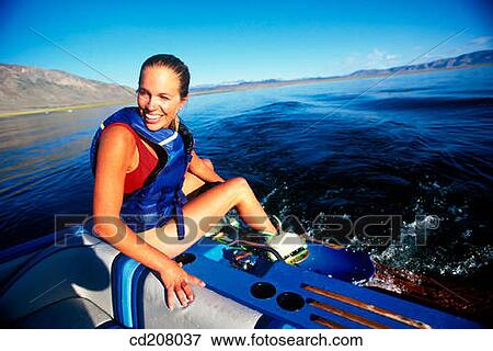 A woman sitting on the back of a boat getting ready to go wake boarding View Large Photo Image Stock Photo - A woman sitting on the back of a boat getting ready to go wake boarding. Fotosearch