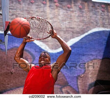 Basketball player slam dunks the ball on a street court View Large Photo Image Stock Image - Basketball player slam dunks the ball on a street court. Fotosearch