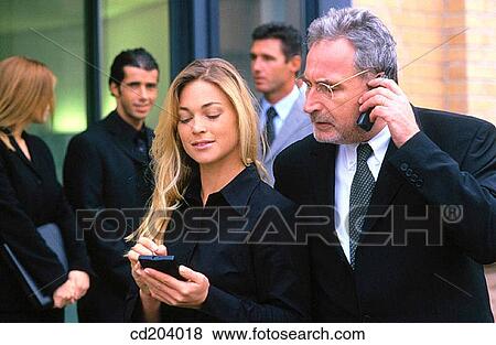 Businessman talking on cell phone, businesswoman with organizer, three businesspeople in the background View Large Photo Image Stock Photo - Businessman talking on cell phone, businesswoman with organizer, three businesspeople in the background. Fotosearch