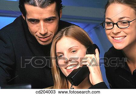 Businesswoman talking on phone, two businesspeople in the background looking interested View Large Photo Image Stock Image - Businesswoman talking on phone, two businesspeople in the background looking interested. Fotosearch